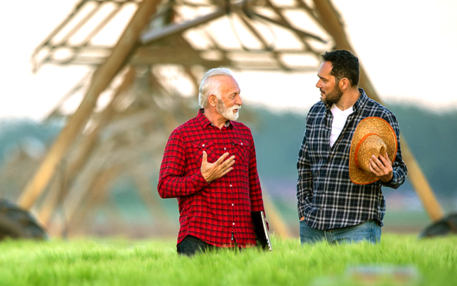 Men in field talking about farming in front of an irrigation pivot.